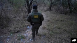 A Border Patrol agent walks along a trail littered with bracelets used by human smuggling groups near the Rio Grande at the U.S.-Mexico border, Feb. 13, 2025, in McAllen, Texas.