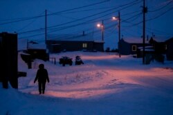 FILE - A woman walks in Toksook Bay, Alaska, a mostly Yup'ik village on the edge of the Bering Sea, Jan. 20, 2020. A judge ruled in favor of tribal nations in a bid to keep Alaska Native corporations from getting part of $8 billion in COVID relief funding