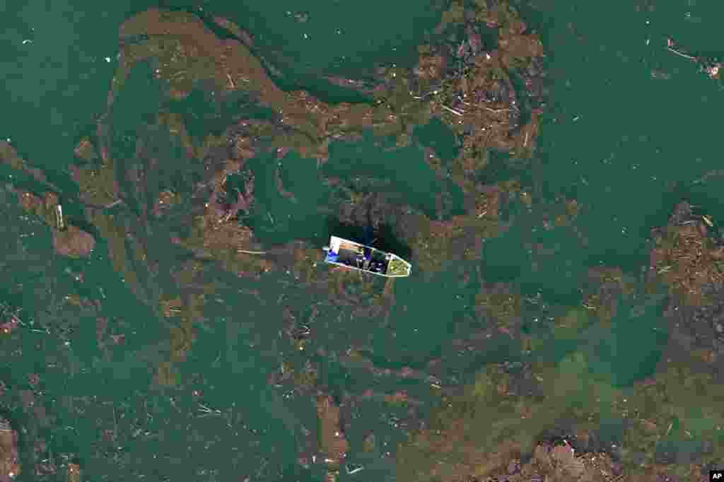 Aerial view of Ibro Mesic rowing his boat through mud and waste after devastating floods and landslides put tons of waste in Jablanicko lake near Ostrozac, Bosnia.