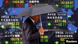 A pedestrian walks past a stock quotation board displaying various countries' share indices, outside a brokerage in Tokyo Oct. 1, 2013. 