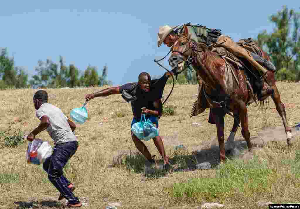 A United States Border Patrol agent on horseback tries to stop a Haitian migrant from entering an encampment on the banks of the Rio Grande near the Acuna Del Rio International Bridge in Del Rio, Texas, Sept. 19, 2021.