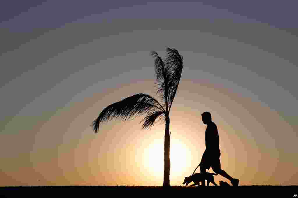 A man walks his dog as the sun sets in Asuncion, Paraguay, Aug. 1, 2020.