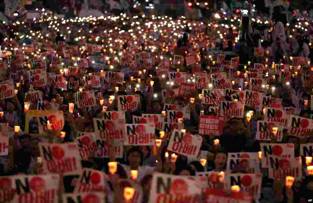 Protesters hold candles and signs during a rally in downtown Seoul, denouncing Japanese Prime Minister Shinzo Abe and demanding the South Korean government abolish its General Security of Military Information Agreement.