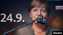 지난 14일 독일 뒤스부르크에서 24일 총선을 앞두고 앙겔라 메르켈 총리의 얼굴이 담긴 대형 포스터를 설치하고 있다.