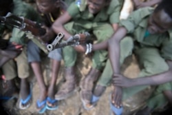FILE - Young boys sit with their rifles Pibor, South Sudan, Feb. 10, 2015.