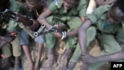 FILE - Young boys sit with their rifles Pibor, South Sudan, 2.10.2015. Inter-communal clashes in December 2020 in the Tonj North County of Warrap state in South Sudan left seven people dead. 