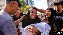 A woman mourns as she holds the shrouded body of her child who was killed during an Israeli strike on a school housing displaced Palestinians in Gaza City, Sept. 21, 2024.