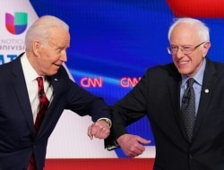 FILE - Former U.S. vice president Joe Biden, left, and Senator Bernie Sanders greet each other with a safe elbow bump before the start of the 11th Democratic Party 2020 presidential debate in a CNN Washington studio in Washington, March 15, 2020.