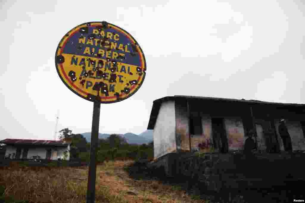 Luxury tourist quarters built during the rule of Mobutu Sese Seko that were destroyed and abandoned in earlier violence now serve as housing for some militias. The park&#39;s bullet-riddled welcome sign indicates the park&#39;s former name.