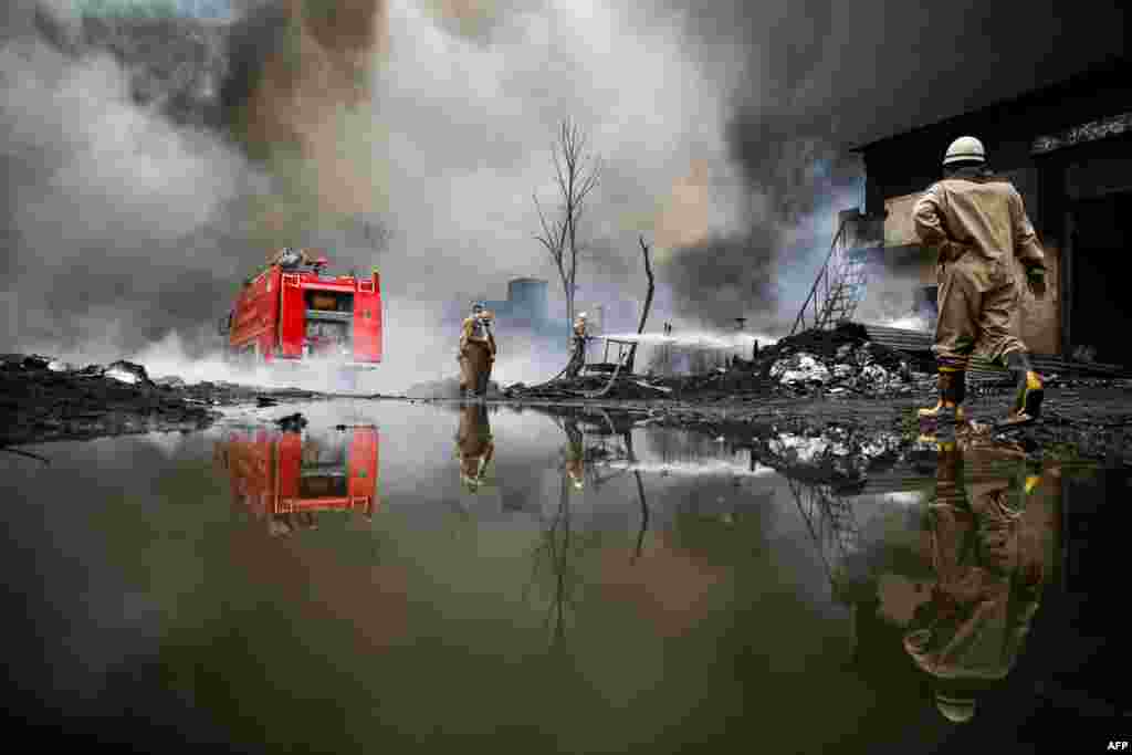A firefighter extinguishes a blaze that broke out at a warehouse in New Delhi, India.