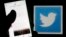 FILE - A man reads tweets on his phone in front of a displayed Twitter logo in Bordeaux, southwestern France, March 10, 2016. 