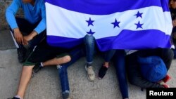 Des adolescents honduriens tenant le drapeau de leur pays en attendant de partir avec une caravane de migrants pour les États-Unis, San Pedro Sula, 14 janvier 2020. (Reuters)