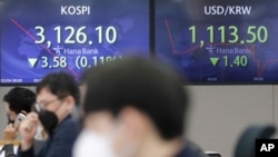 Currency traders watch computer monitors near screens showing the Korea Composite Stock Price Index, left, and the foreign exchange rate between US dollar and South Korean won at the foreign exchange dealing room in Seoul, South Korea, Feb. 4, 2021.