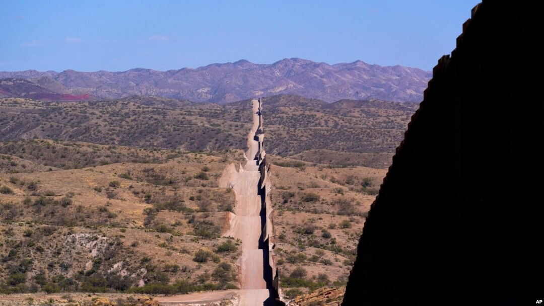 FILE - In this May 19, 2021 photo the border wall stretches along the landscape near Sasabe, Ariz. The bodies of an unusually large number of migrants who died in Arizona's borderlands are being recovered this summer amid record temperatures.