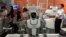 FILE - Visitors to the 21st China Beijing International High-tech Expo look at robots and helicopter drone displayed in Beijing, China, May 17, 2018. 