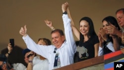 El candidato presidencial opositor Edmundo González Urrutia levanta su mano junto a la de la dirigente María Corina Machado en un acto con jóvenes en la Universidad Central de Venezuela, en Caracas, el 14 de julio de 2024.