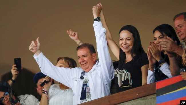 El candidato presidencial opositor Edmundo González Urrutia levanta su mano junto a la de la dirigente María Corina Machado en un acto con jóvenes en la Universidad Central de Venezuela, en Caracas, el 14 de julio de 2024.