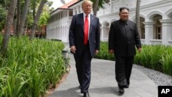 Le président américain Donald Trump et le dirigeant nord-coréen Kim Jong-Un marchent au sortir d’un déjeuner à l’hôtel Capella sur l'île de Sentosa à Singapour, le 12 juin 2018 (AP Photo/Evan Vucci).