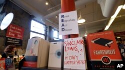 Books are displayed under a sign at the Harvard Book Store, March 9, 2017, in Cambridge, Mass. Readers have been flocking to classic works of dystopian fiction in the first months of Donald Trump's presidency.