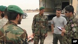 Afghan Air Force Sergeant Hayatullah Bahar Jawazjani, far right, comunicates with his compatriots, Aug 2010. He has been working with US military personnel for the past six months and has taken on a leadership role.