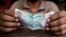 FILE - A cashier holds an Indian rupee. 