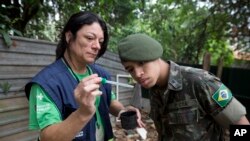 A health agent from Sao Paulo's Public health secretary shows an army soldier Aedes aegypti mosquito larvae that she found during clean up operation against the insect, which is a vector for transmitting the Zika virus, in Sao Paulo, Brazil, Jan. 20, 2016.