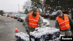 FILE - Michigan National Guard members distribute water to a line of residents in their cars in Flint, Michigan, Jan. 21, 2016. 