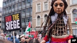 Little Amal, a 12-foot puppet in the image of a 10-year-old Syrian refugee, joins a pro-Palestinian demonstration as protesters hold placards and flags in London on Jan. 13, 2024.