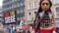 Little Amal, a 12-foot puppet in the image of a 10-year-old Syrian refugee, joins a pro-Palestinian demonstration as protesters hold placards and flags in London on Jan. 13, 2024.