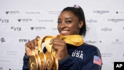 Simone Biles of the United States shows her five gold medals she won at the Gymnastics World Championships in Stuttgart, Germany, Oct. 13, 2019.