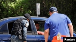 FILE -- An agent of the U.S. Department of Homeland Security and an officer of the Guatemalan border police (DIPAFRONT) question a passenger at a checkpoint in El Progreso, Guatemala, Oct. 17, 2019. 