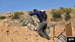 Bolivian teacher Wilfredo Negrete Jaldin pushes his bike carrying a board on his way to his students&#39; homes in Aiquile.