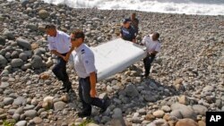 FILE - French police officers carry a piece of debris, the first trace of Malaysia Airlines Flight 370, in Saint-Andre, Reunion Island.