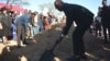 Botswana President Duma Boko throws sand onto the grave during the burial and memorial service of the late Pitseng Gaoberekwe in Metsiamanong village, Central Kalahari Game Reserve (CKGR), on Dec. 10, 2024.