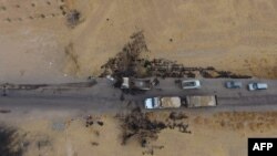 Vehicles are seen near a destroyed truck at the spot where Abu Hassan al-Muhajir, the Islamic State group's spokesman, was reportedly killed in a raid in the northern Syrian village of Ayn al-Bayda near Jarablus, Oct. 28, 2019.
