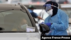  A health worker conducts a COVID-19 test at the St. Vincent's Bondi Beach COVID-19 drive through testing clinic on Dec. 22, 2021, in Sydney. 