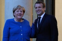 French president Emmanuel Macron welcomes German Chancellor Angela Merkel prior to their meeting at the Elyse Palace in Paris, Sunday, Oct. 13, 2019. (AP Photo/Francois Mori)