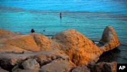 FILE - A tourist enjoys the sun setting over the Red Sea in Sharm El-Sheikh, Egypt, June 25, 2015.