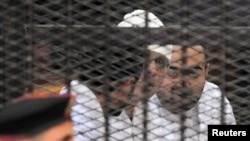 FILE - Political activists Ahmed Maher, Ahmed Douma (L) and Mohamed Adel (R) of the 6 April movement look on from behind bars in Abdeen court in Cairo, December 22, 2013. Three leading Egyptian activists were sentenced to three years in prison each.