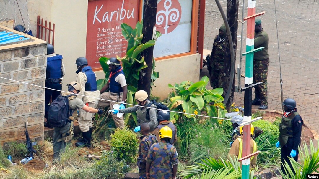 Foreign forensic experts, flanked by Kenyan military personnel, check the perimeter walls around Westgate shopping mall in Nairobi Sept. 25, 2013. 