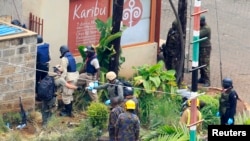Foreign experts, flanked by military personnel, check the walls around the Westgate shopping mall in Nairobi, Sept. 25, 2013. 