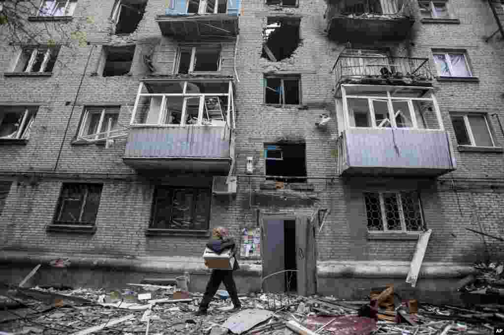 A man carries his belongings from an apartment building damaged from shelling in Slovyansk, eastern Ukraine, June 12, 2014.