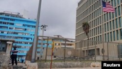 ARCHIVO - La bandera estadounidense ondea junto a un agente de seguridad que custodia la embajada de Estados Unidos en La Habana, Cuba, el 12 de diciembre de 2023. 