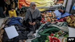 FILE —A woman sits among Palestinians at Al-Shifa hospital in Gaza City after they were injured in an early morning incident when residents rushed toward aid trucks in Gaza City on February 29, 2024.