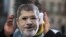 A man covers his face with a mask of Egypt President Mohammed Morsi during a protest in front of the chancellery against the visit of Morsi prior to a meeting of him with German Chancellor Angela Merkel in Berlin, Germany, January 30, 2013.