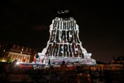 An image stating 'No America Without Black America' is projected on to the pedestal of the statue of confederate Gen. Robert E. Lee on Monument Avenue, July 22, 2020, in Richmond, Va.