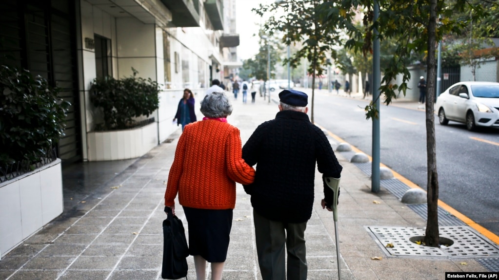 FILE - A couple walk on a sidewalk in Santiago, Chile, Wednesday on May 3, 2017. 