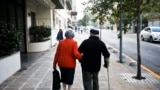 FILE - A couple walk on a sidewalk in Santiago, Chile, Wednesday on May 3, 2017. 