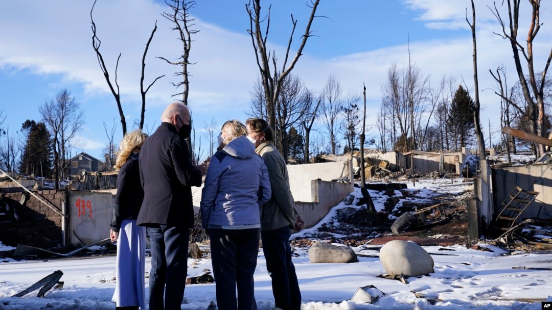 President Joe Biden and first lady Jill Biden talk with people as they tour a neighborhood in Louisville, Colo., Jan. 7, 2022, that was impacted by the recent wildfire. At left is Colorado Gov. Jared Polis. 