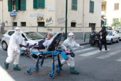 Medical staff in full protective gear carry a patient on a stretcher down a street in Naples, as the spread of coronavirus continues, Italy, April 2, 2020.